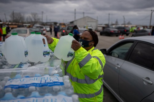 Volunteer Elizabeth Murray helps hand water to local residents at Butler Stadium after the city of Houston implemented a boil water advisory following an unprecedented winter storm in Houston, Texas, U.S., February 21, 2021. REUTERS/Adrees Latif