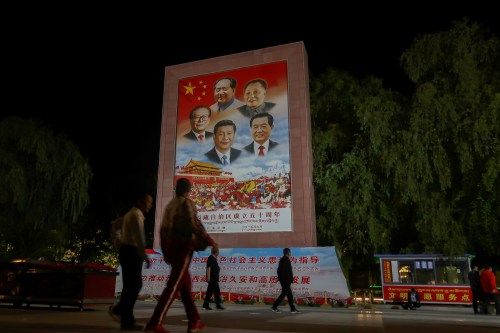 People walk past a poster showing Chinese President Xi Jinping and former Chinese leaders Mao Zedong, Deng Xiaoping, Jiang Zemin and Hu Jintao on the Potala Palace Square during a government-organised media tour to Lhasa, Tibet Autonomous Region, China June 1, 2021. Picture taken June 1, 2021. REUTERS/Martin Pollard