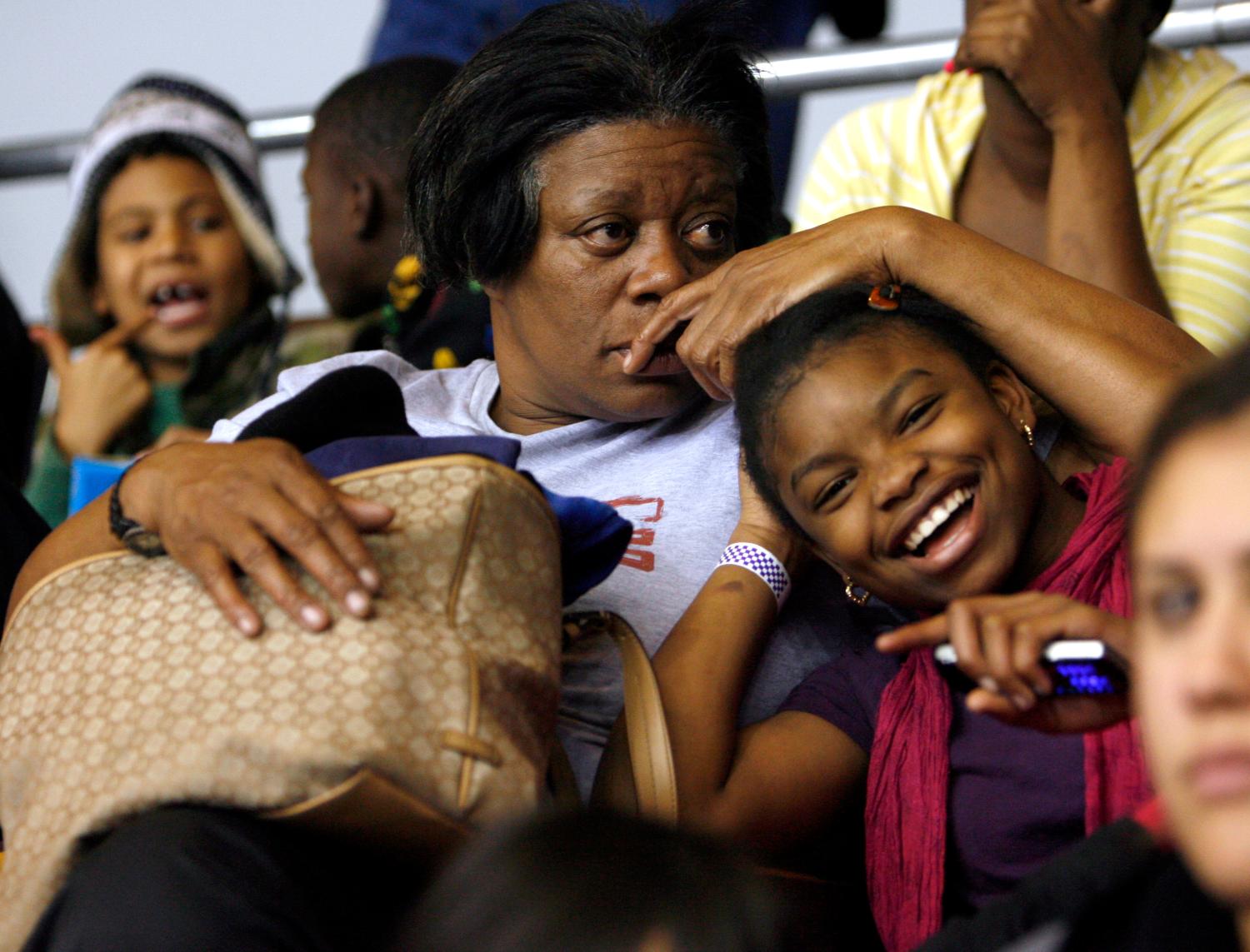 Linda Dennis (L) sits with her 11-year-old family member Sharee Nelo (R) inside the L.A. Sports Area in Los Angeles, California, December 20, 2009. Thousands of bicycles and toys were given away to families in need during The Dream Center Christmas in the City event. Dennis and her family waited in line outside for over 16 hours, including sleeping overnight, to ensure they were one of the families to receive the and gifts.     REUTERS/Danny Moloshok (UNITED STATES - Tags: SOCIETY)