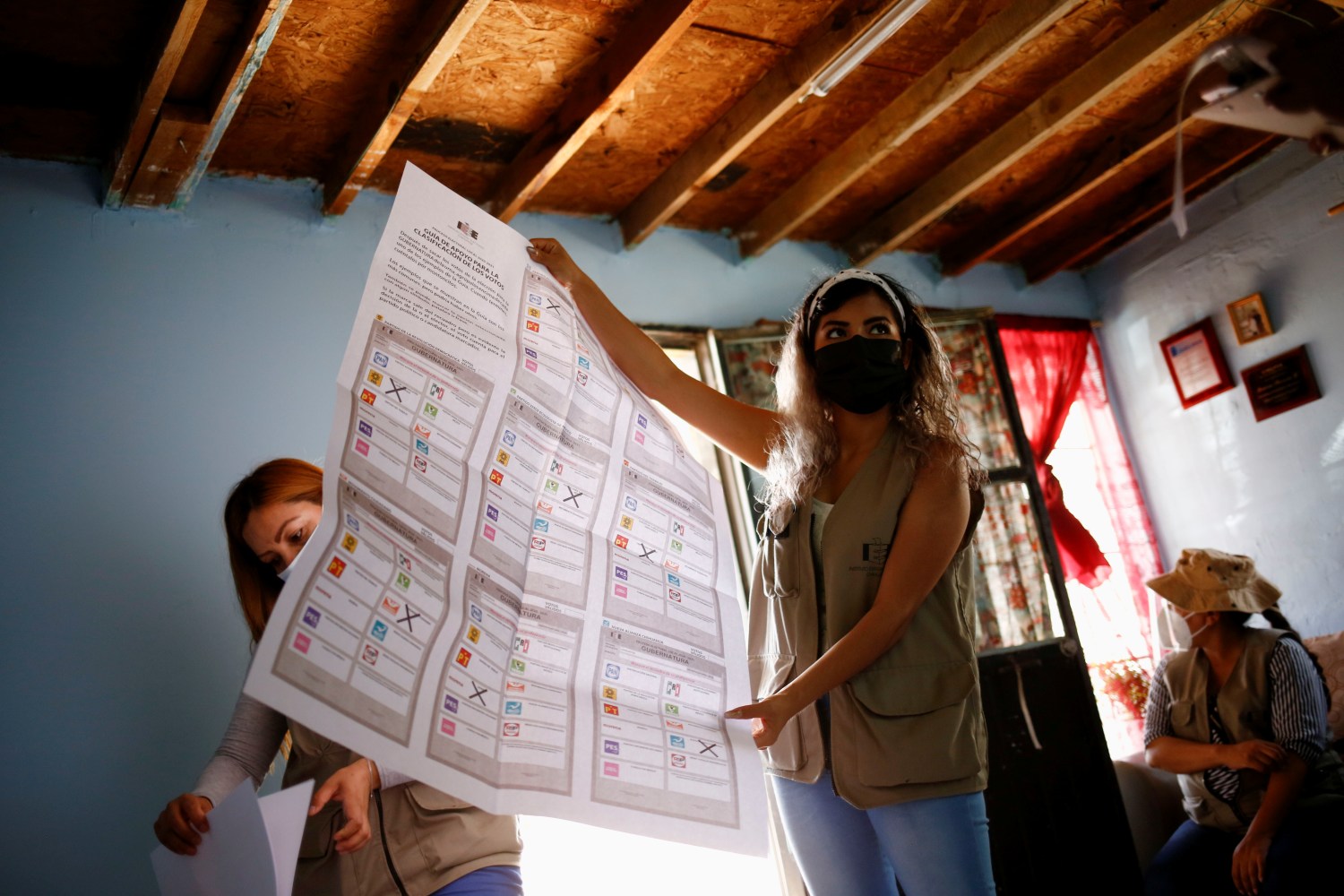 An electoral worker shows voting material to a woman who was selected by the National Electoral Institute (INE) to act as a president of a polling station, ahead of the mid-term elections on June 6, at the Anapra neighborhood, in Ciudad Juarez, Mexico June 1, 2021. REUTERS/Jose Luis Gonzalez