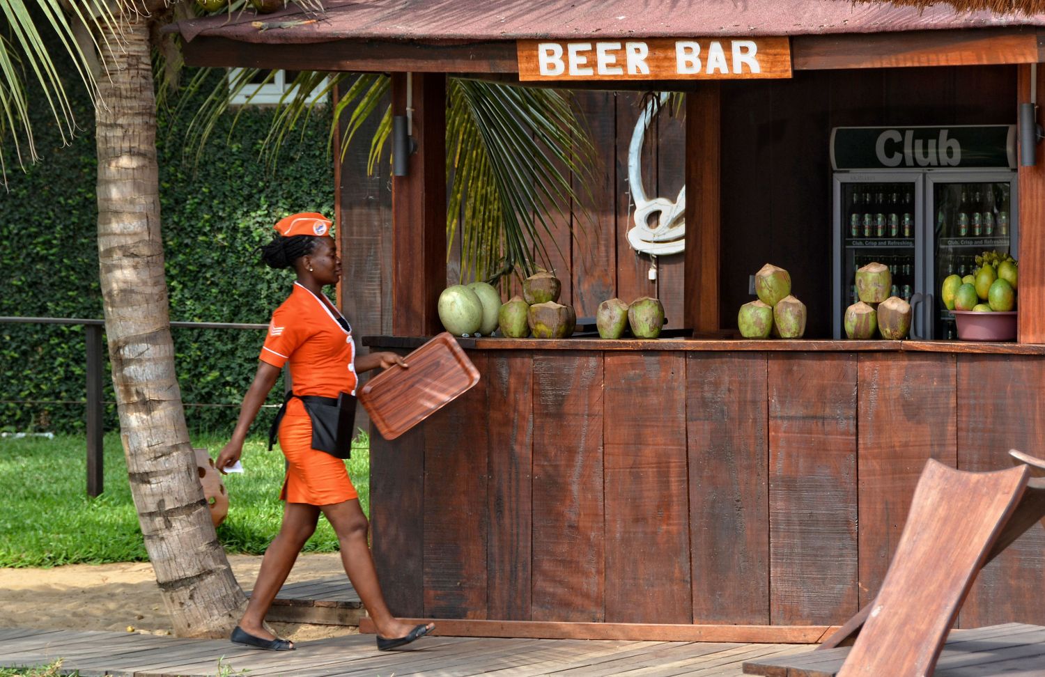 Waitress and an African open-air bar with coconuts and beer. Travel and vacation in West Africa. Aqua Safari Resort. Ghana, Volta, Ada - January 14, 2017
