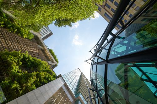 Low angle shot of modern glass buildings and green with clear sky background