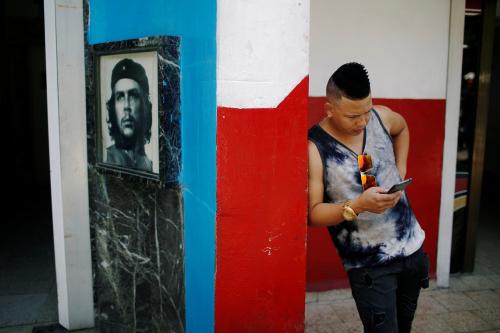 A young Cuban checks his phone at an internet hotspot next to a picture of late revolutionary hero Ernesto "Che" Guevara in Havana, Cuba August 10, 2018. Picture taken August 10, 2018. REUTERS/Tomas Bravo