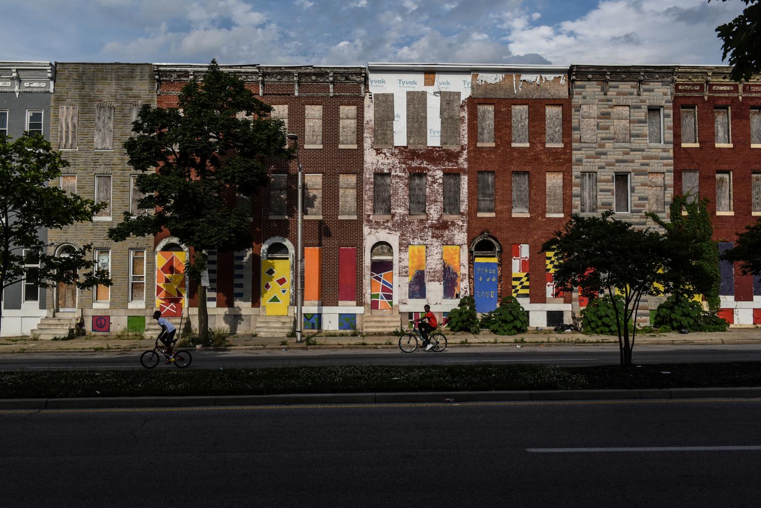 Young boys ride their bikes past boarded-up and abandoned row of houses in Baltimore, Maryland, U.S., May 26, 2019. REUTERS/Stephanie Keith  SEARCH "KEITH TOWNES" FOR THIS STORY. SEARCH "WIDER IMAGE" FOR ALL STORIES. - RC187F4B9C50