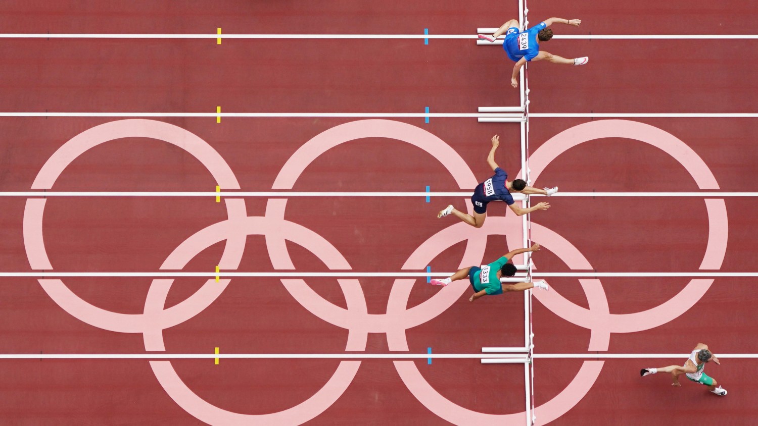 Tokyo 2020 Olympics - Athletics - Men's 400m Hurdles - Round 1 - OLS - Olympic Stadium, Tokyo, Japan - July 30, 2021. Athletes compete as Olympic rings are seen REUTERS/Peter Jebautzke