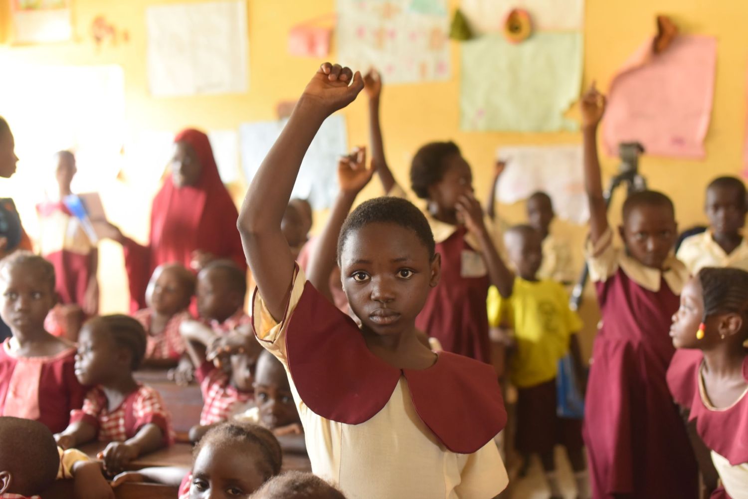 A student in a Nigerian classroom raises her hand.