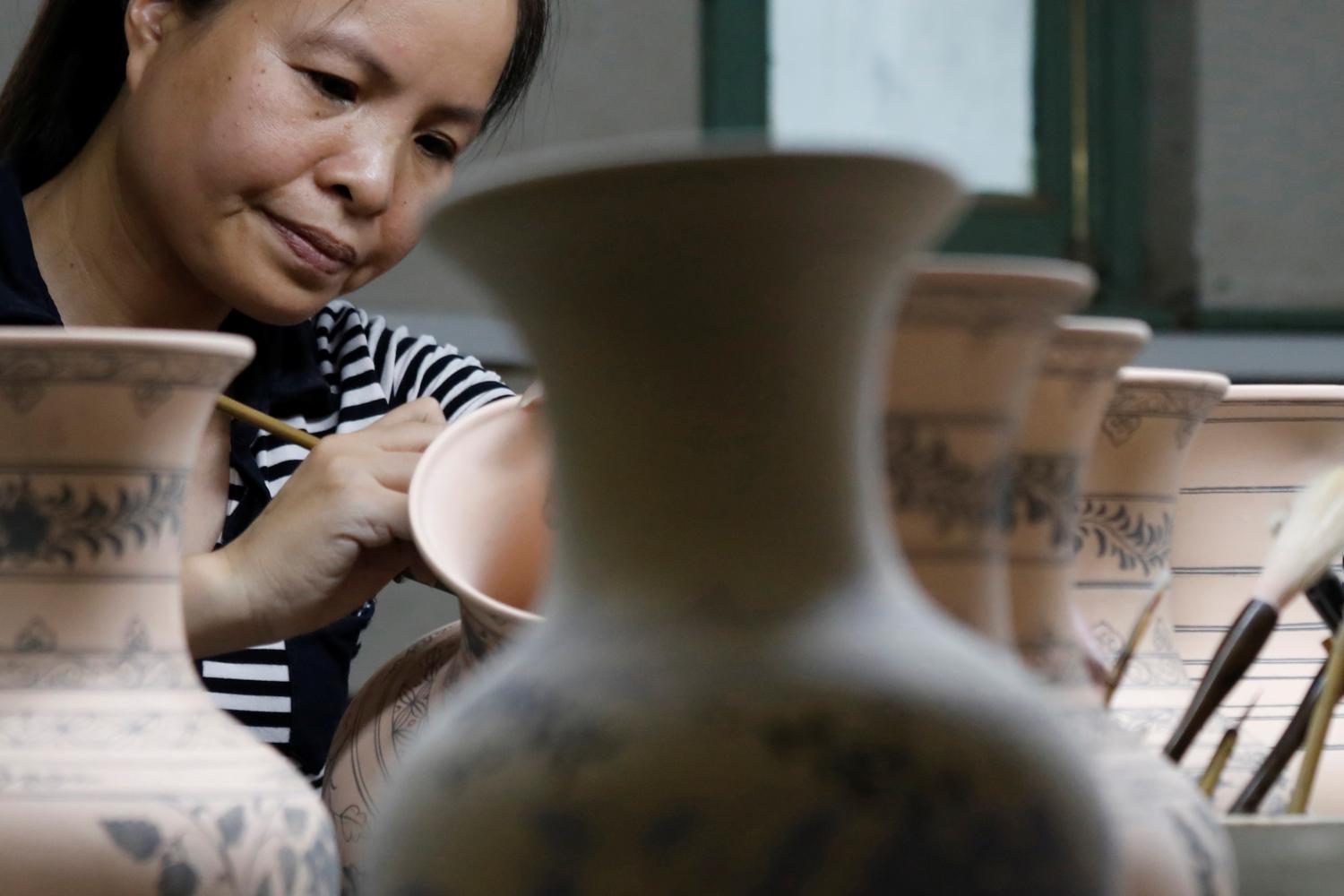 A woman paints on ceramic products at an assembly of Hai Duong ceramic factory in Hai Duong province, Vietnam July 24, 2020. REUTERS/Kham