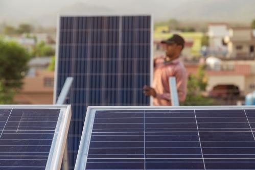 A worker in India installs a solar panel.