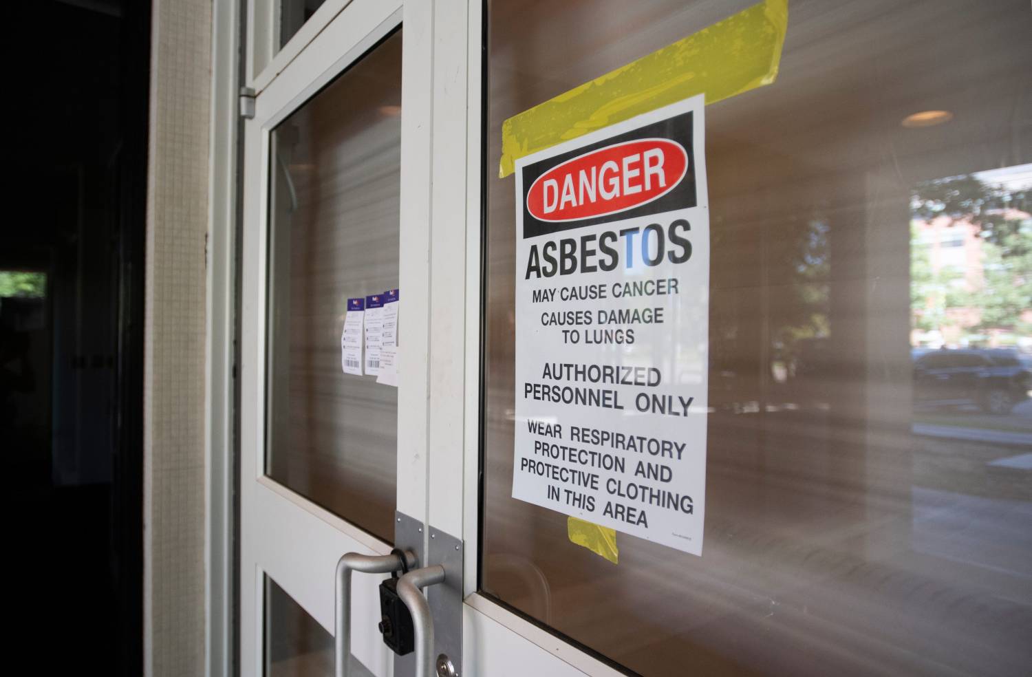 A sign warns of asbestos on the doorway to the office tower at 215 W. Oak St. in Fort Collins, Colo. on Tuesday, Sept. 1, 2020.090120 Asbestos 01 Bb