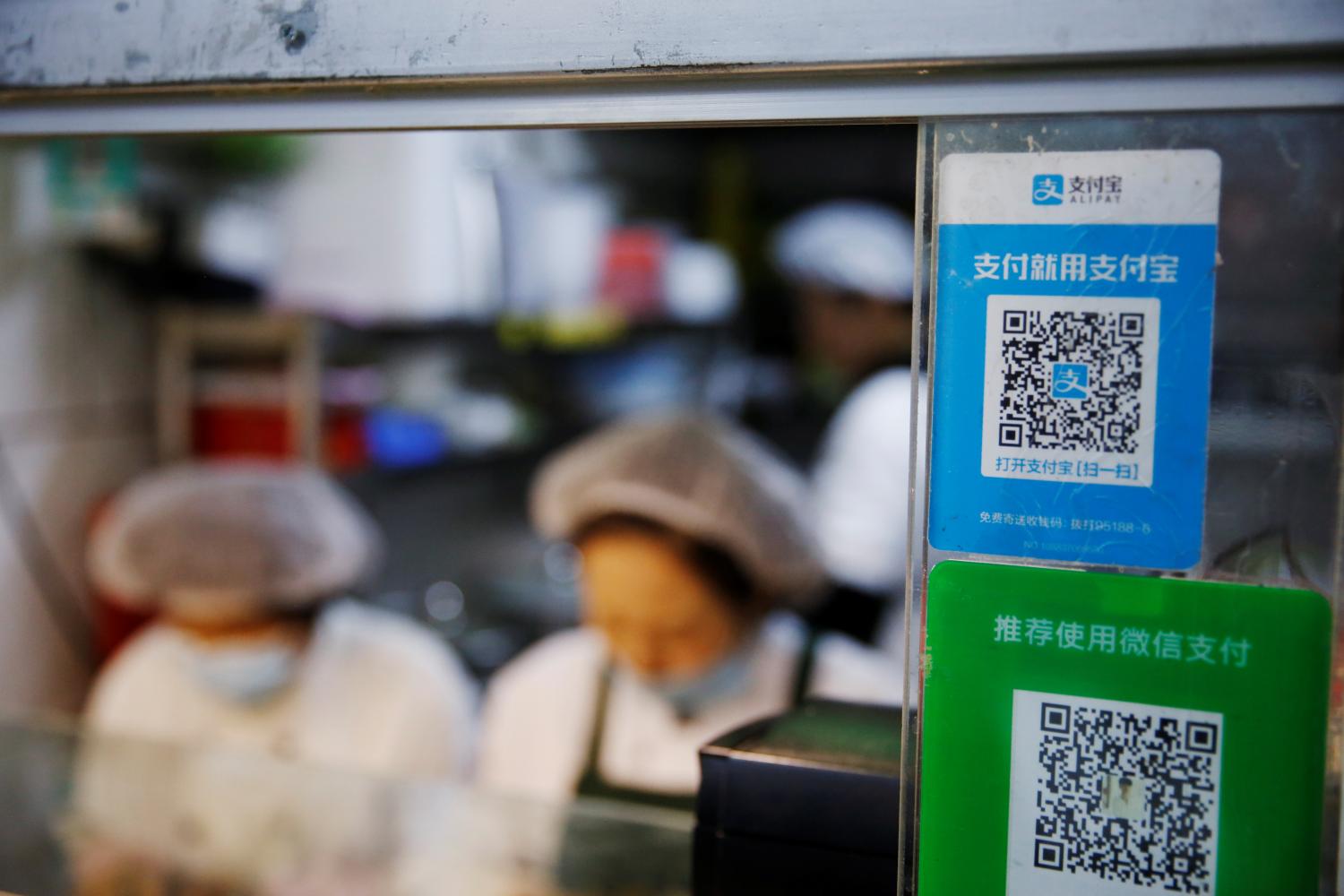 A QR code of digital payment device Alipay by Ant Group, an affiliate of Alibaba Group Holding, is seen next to a QR code of WeChat Pay at a food stall inside a market, in Beijing, China November 2, 2020. REUTERS/Tingshu Wang