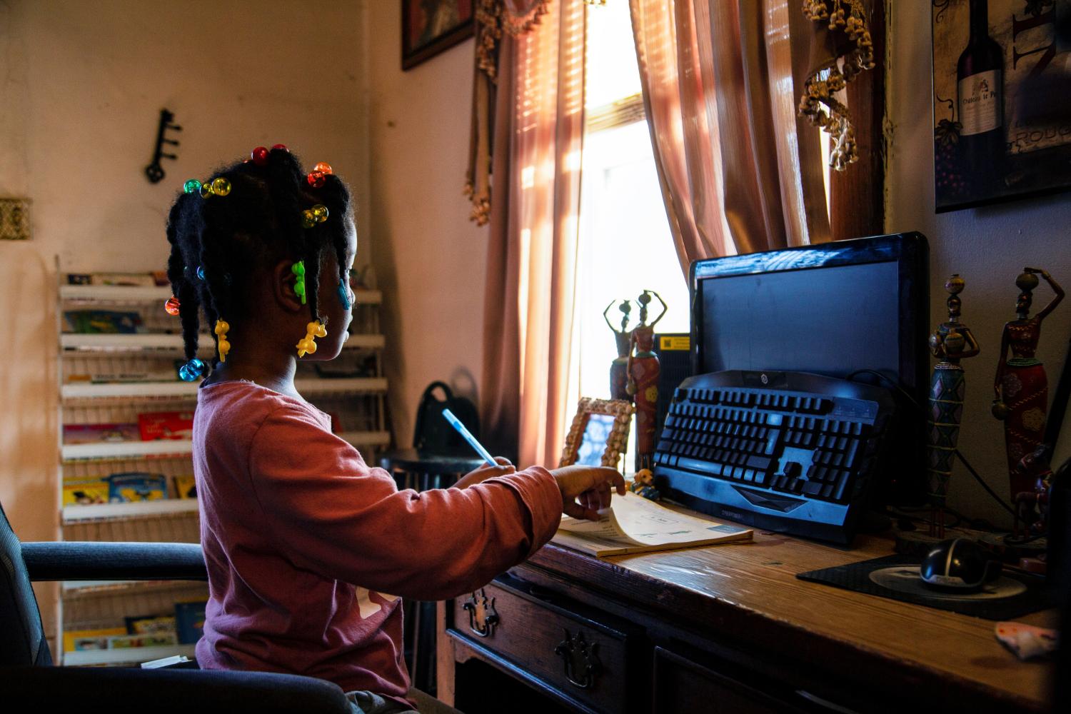 Child looks at turned off computer monitor during remote school