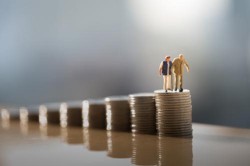 Miniatures of elderly people on stacks of coins.