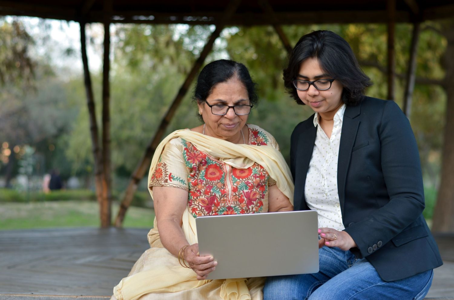 Two women in India work on a computer together.