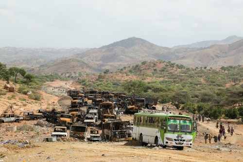 Villagers return from a market to Yechila town in south central Tigray walking past scores of burned vehicles, in Tigray, Ethiopia, July 10, 2021. REUTERS/Giulia Paravicini