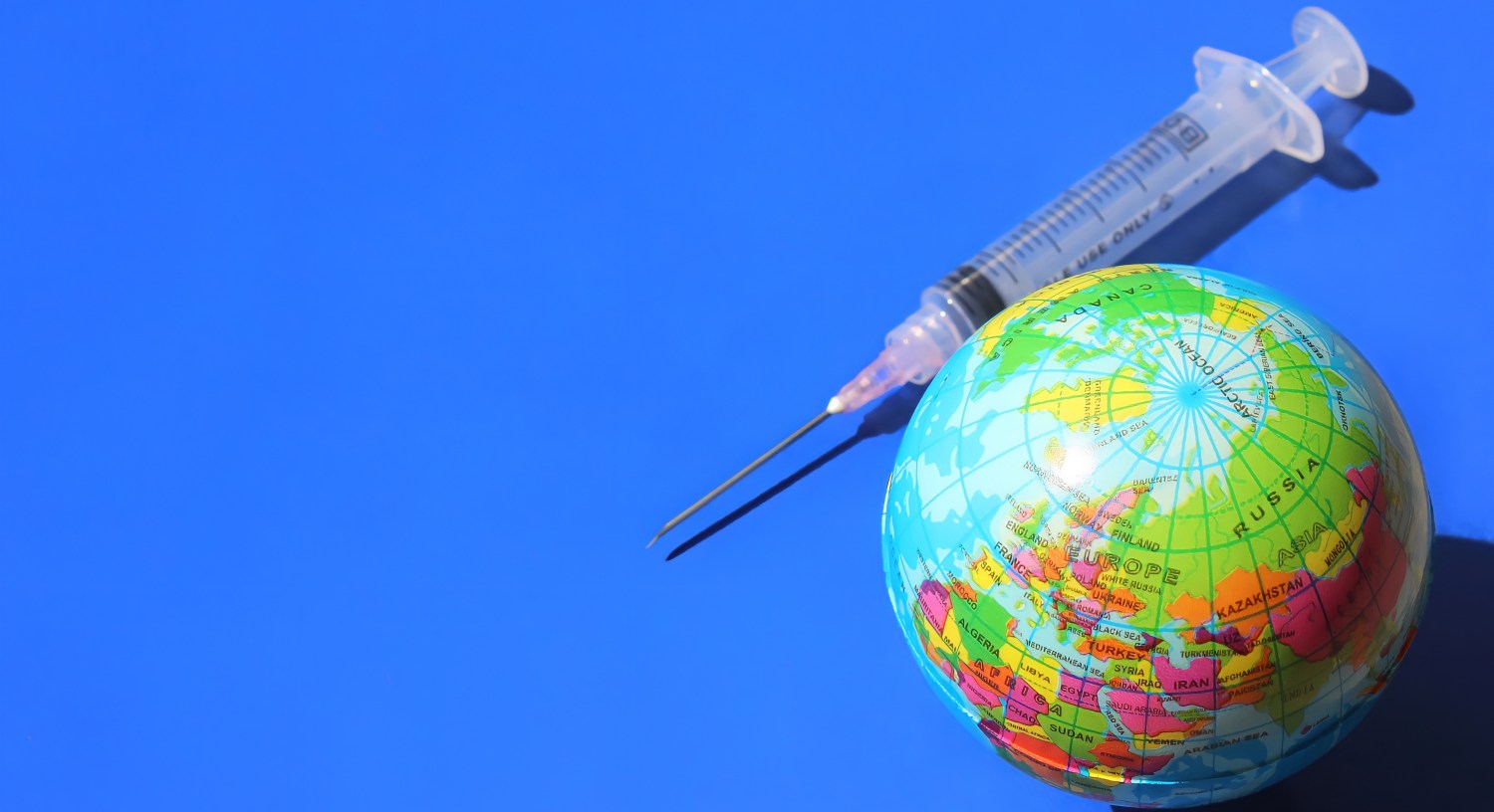 A globe and syringe on a blue background
