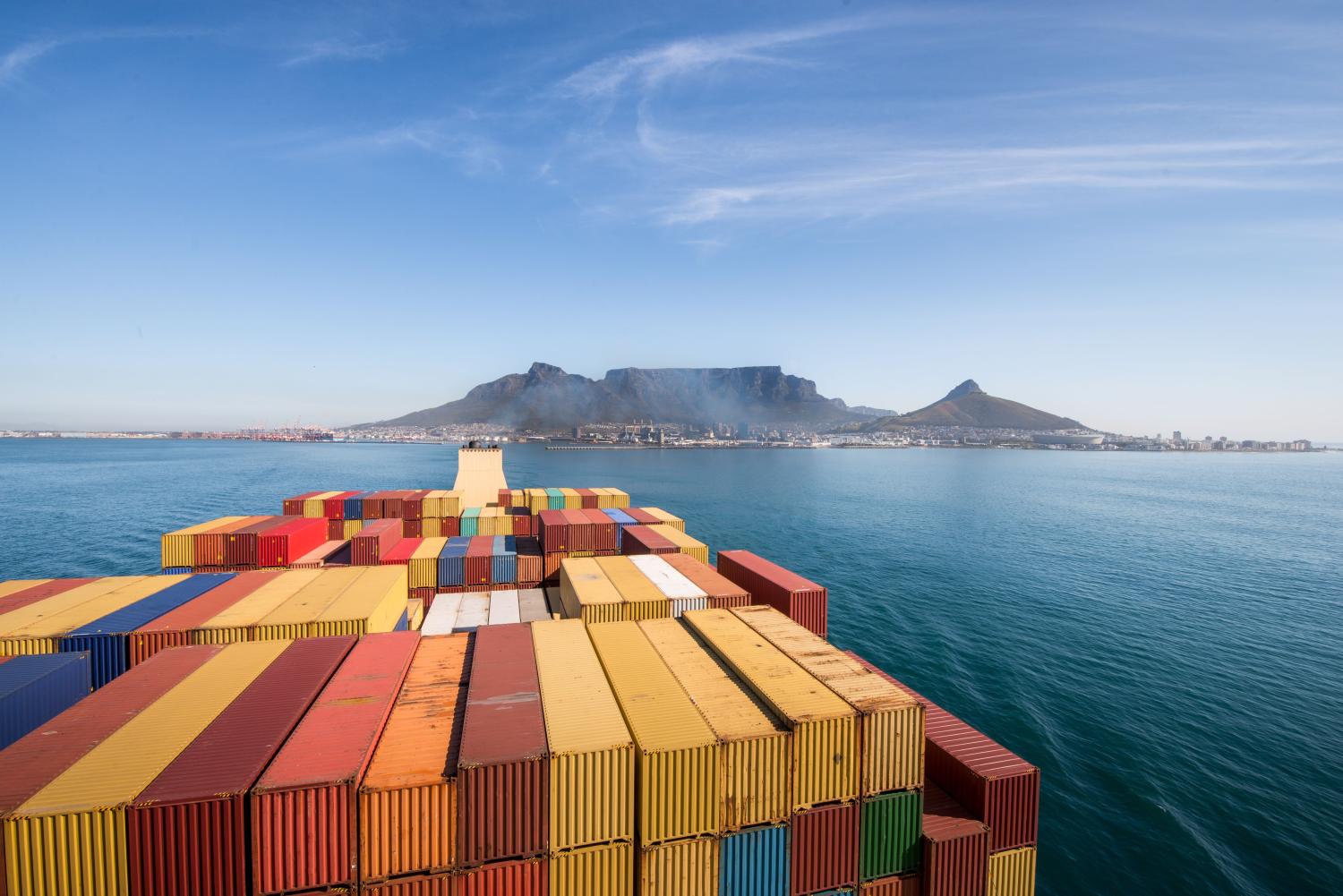 Large stacked container ship leaving the port of Cape Town with Table mountain and the city in the background, South Africa.