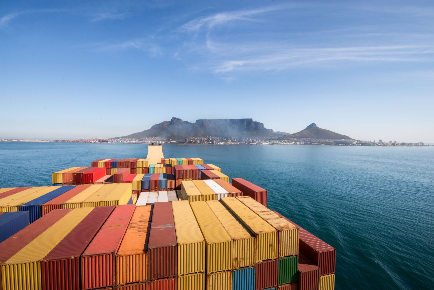 Large stacked container ship leaving the port of Cape Town with Table mountain and the city in the background, South Africa.