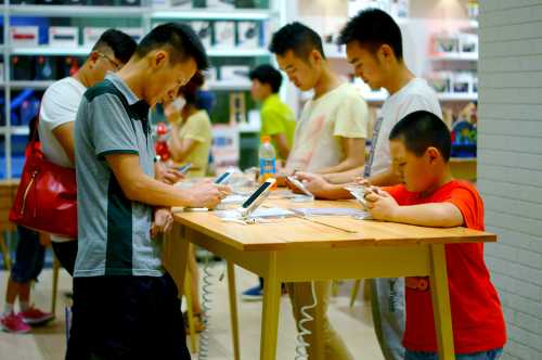 --FILE--Chinese customers try out Apple's iPhone 6 or 6 Plus smartphones at a store in Yichang city, central China's Hubei province, 9 July 2015.The number of Chinese mobile phone users accounted for 94.5% of its total population by the end of June, latest data showed. In the first half, China saw 6.88 million new mobile phone users, bringing the country's total mobile phone users to 1.29 billion, the Ministry of Industry and Information Technology (MIIT) said in a statement. The ratio of mobile phone users to population was higher than 100% in nine provincial-level regions, including Beijing, Shanghai, as well as provinces of Guangdong and Zhejiang. The number of users choosing broadband mobile internet services (3G and 4G services) reached 674 million by the end of June, accounting for 52.1% of all mobile phone users.No Use China. No Use France.