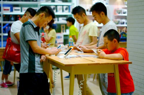 --FILE--Chinese customers try out Apple's iPhone 6 or 6 Plus smartphones at a store in Yichang city, central China's Hubei province, 9 July 2015.The number of Chinese mobile phone users accounted for 94.5% of its total population by the end of June, latest data showed. In the first half, China saw 6.88 million new mobile phone users, bringing the country's total mobile phone users to 1.29 billion, the Ministry of Industry and Information Technology (MIIT) said in a statement. The ratio of mobile phone users to population was higher than 100% in nine provincial-level regions, including Beijing, Shanghai, as well as provinces of Guangdong and Zhejiang. The number of users choosing broadband mobile internet services (3G and 4G services) reached 674 million by the end of June, accounting for 52.1% of all mobile phone users.No Use China. No Use France.