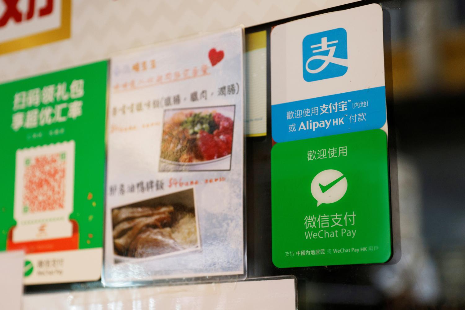 Logos for digital payment services Alipay by Ant Group, an affiliate of Alibaba Group Holding and WeChat Pay by Tencent Holdings are displayed outside a restaurant, in Hong Kong, China November 1, 2020. REUTERS/Tyrone Siu