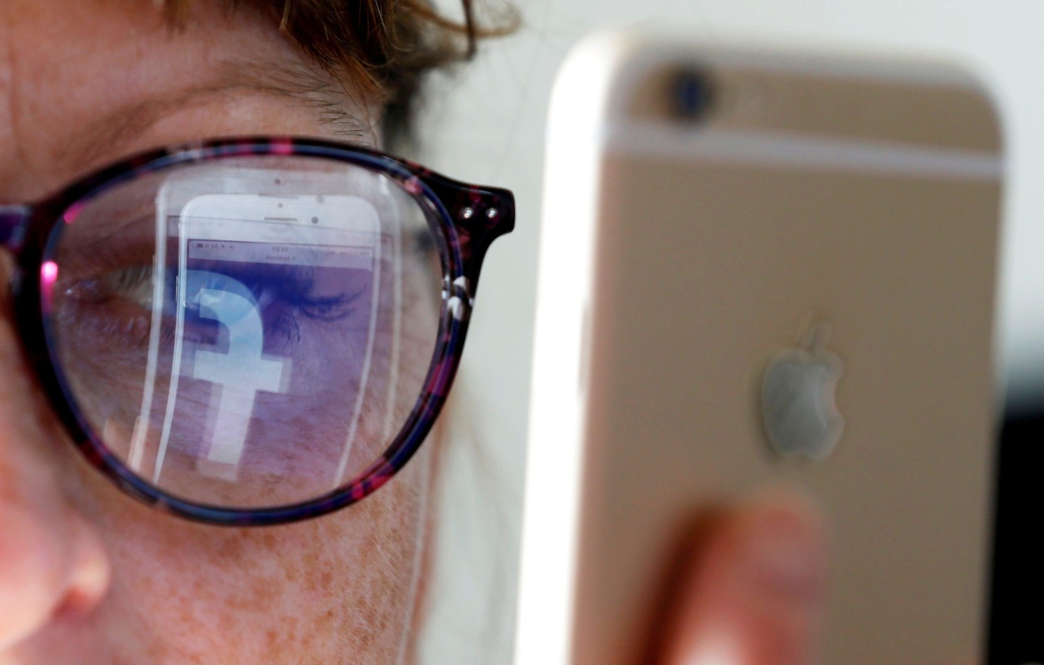 Facebook logo reflected in glasses from phone.