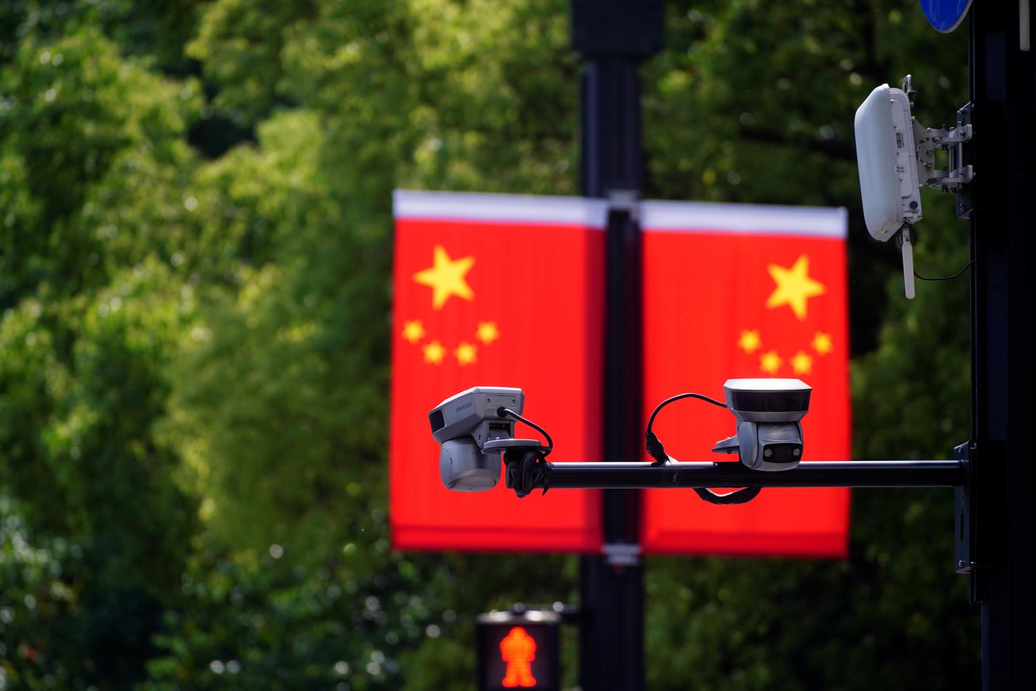 Surveillance cameras are seen mounted in front of two Chinese flags.