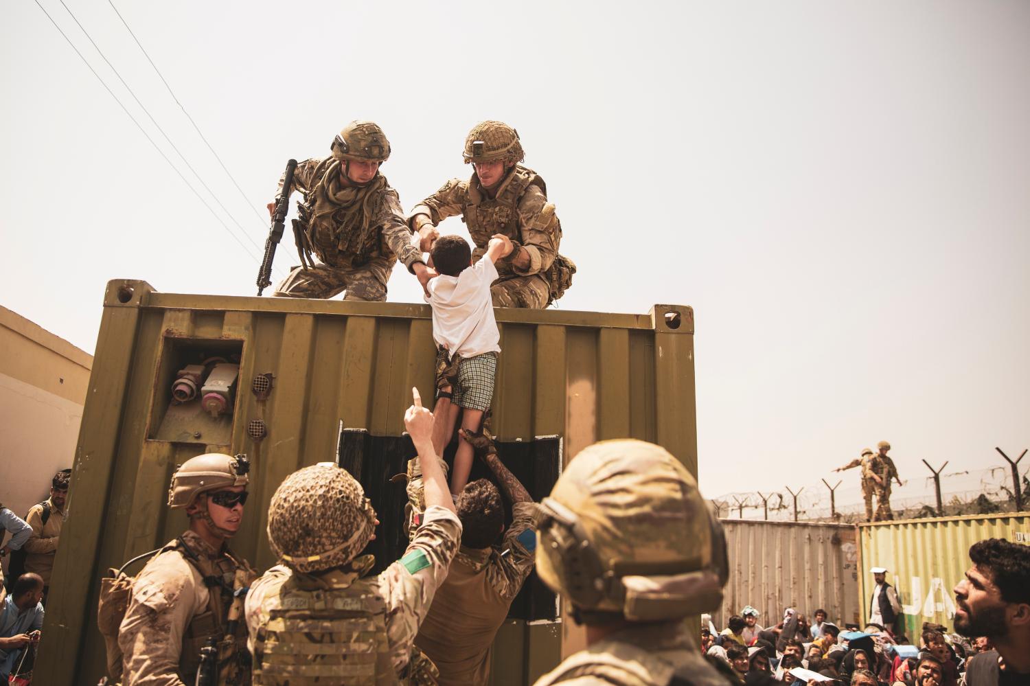 British, Turkish and US soldiers assist a child during the evacuation of civilians at Hamid Karzai International Airport.