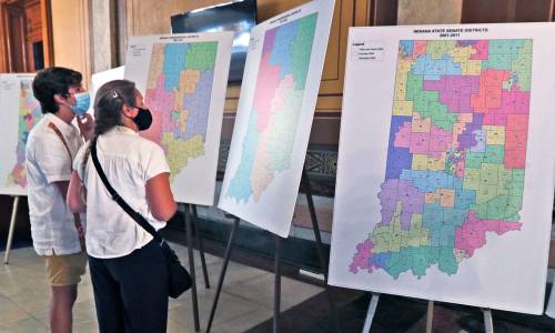 Benjamin Rascon Gracia, left, and Jane Ramirez look at old district maps in the lobby outside the House Chambers after a legislative redistricting hearing Wednesday, Aug. 11, 2021 at the Indiana Statehouse in Indianapolis.Legislative Redistricting Hearing Open To Public