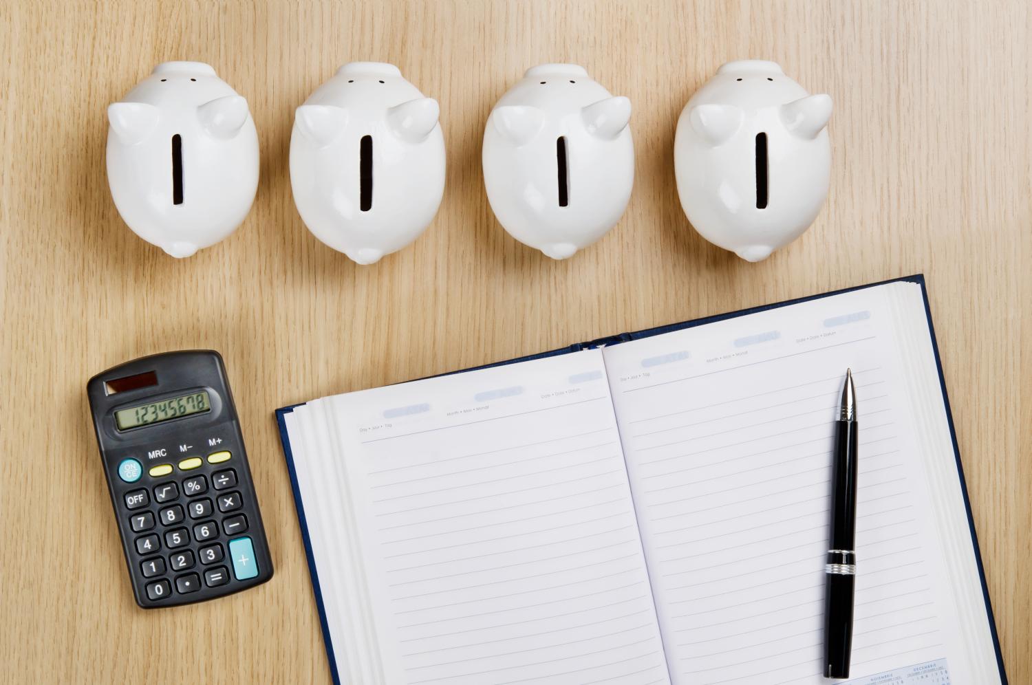 multiple small piggy banks with a calculator and a ledger.