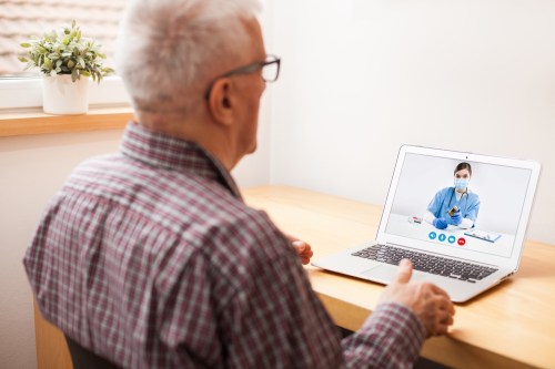 Young e-doctor consulting elderly man,online video help line virtual medical appointment,GP prescribing medication to senior patient,telemedicine diagnosis,tele visit remote health concept
