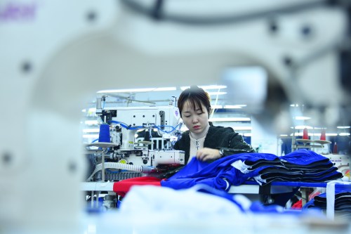 Workers make clothes at an apparel manufacturing company in Enshi city, south China's Hubei province, 21 November 2020.Xuan'en County introduced apparel manufacturing enterprises beside the relocation sites in Shadaogou Town and Gaoluo Town to help with employment. So far, it has helped more than 900 people who were relocated to obtain employment and increase income.No Use China. No Use France.