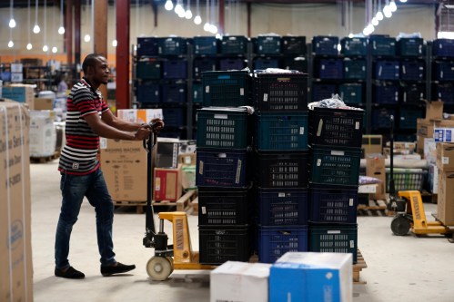 A staff member of on-line retailer Jumia, pushes a cart loaded with goods at the company's warehouse in Lagos April 10, 2014. There are two main reasons people shop online: it's cheaper or they can't be bothered with a trip to the store. And in Lagos, a city of 21 million people, a trip to the store can kill your entire day if you lose the traffic lottery. Jumia has 100,000 Nigerian customer accounts and sales are increasing by 15 percent a month.     REUTERS/Akintunde Akinleye   (NIGERIA - Tags: BUSINESS)