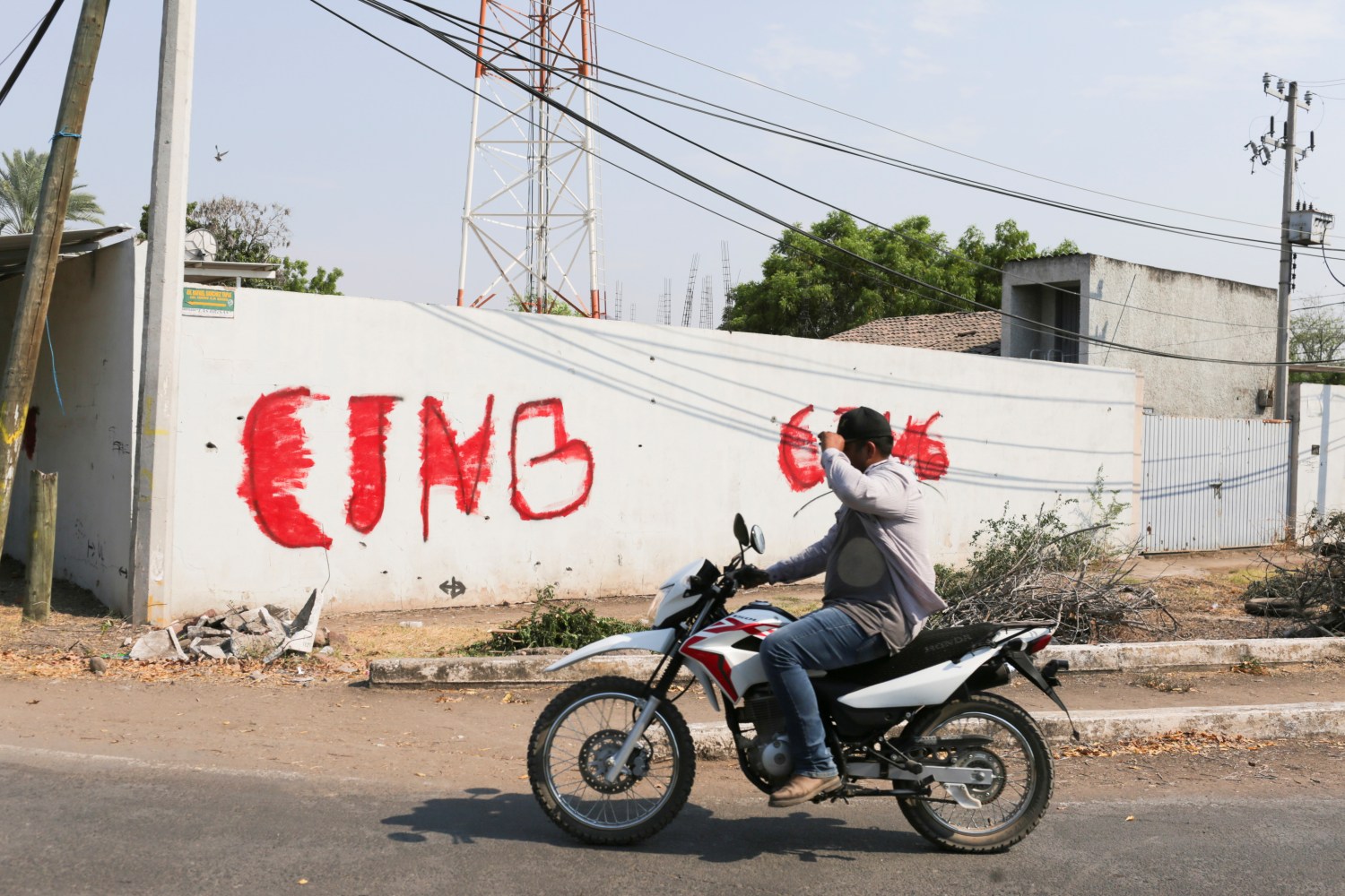 A motorist passes by a wall with a graffiti of the Jalisco New Generation Cartel (CJNG) in El Aguaje after the visit of Vatican's ambassador to Mexico Franco Coppola to the area and to the municipality of Aguililla, an area where the Jalisco New Generation Cartel (CJNG) and local drug gangs are fighting to control the territory, in Michoacan state, Mexico April 23, 2021. REUTERS/Alan Ortega