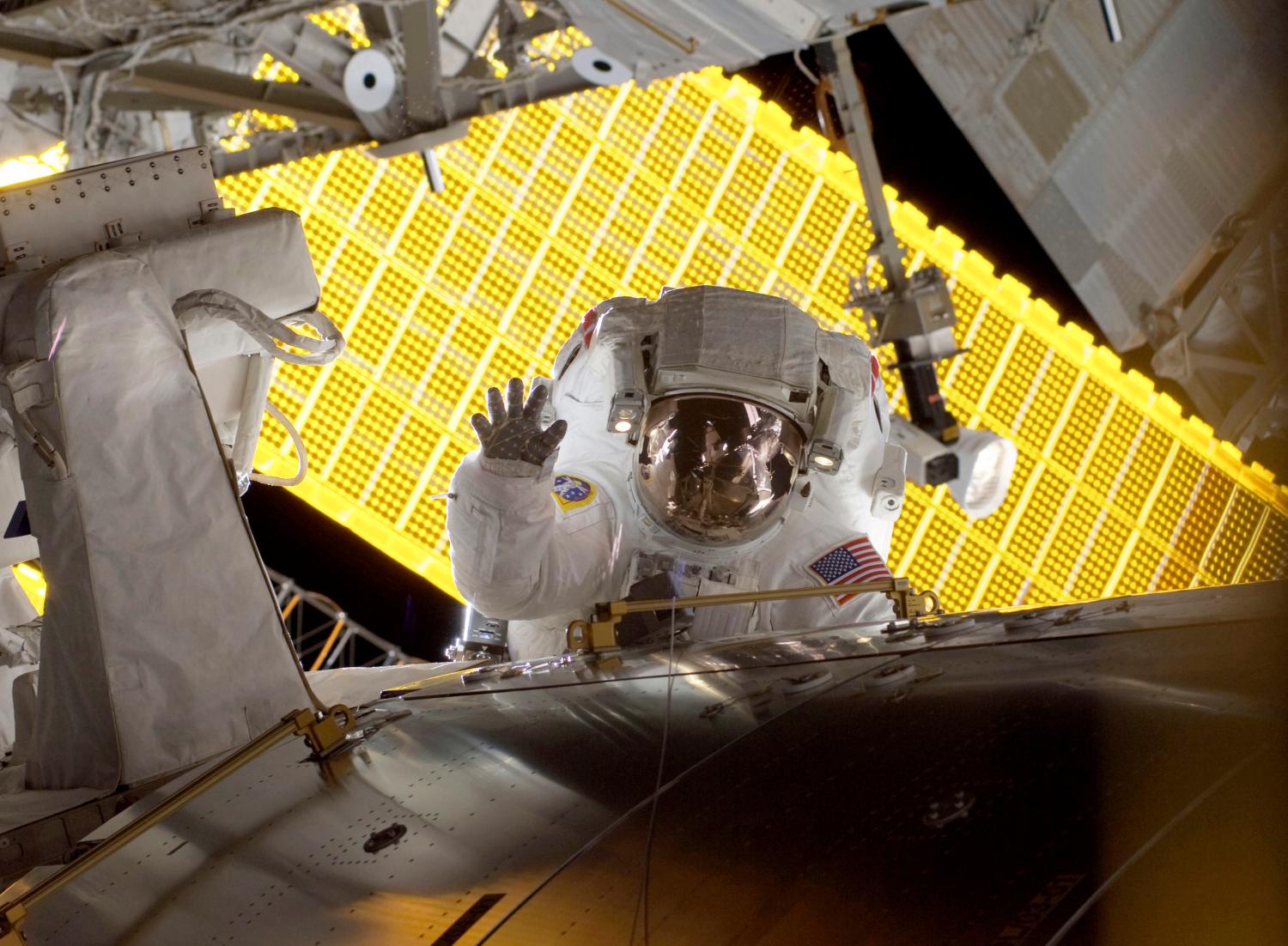 Astronaut Nicole Stott, STS-128 mission specialist waves as she pauses during the mission's first spacewalk with the International Space Station's solar panels as a backdrop as construction and maintenance continue on the International Space Station in this NASA handout photo taken September 1, 2009.