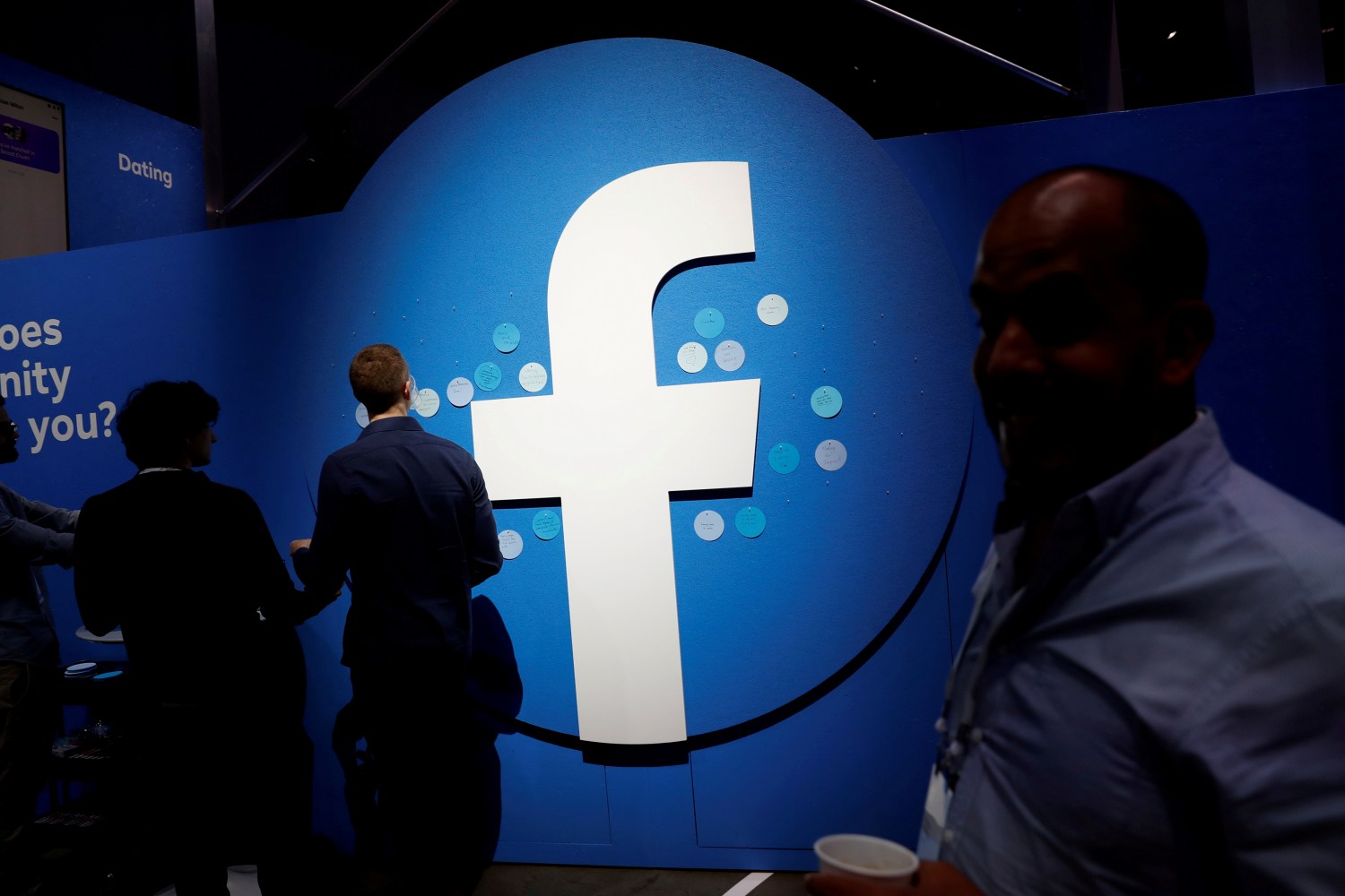 Attendees walk past a Facebook logo during Facebook Inc's F8 developers conference