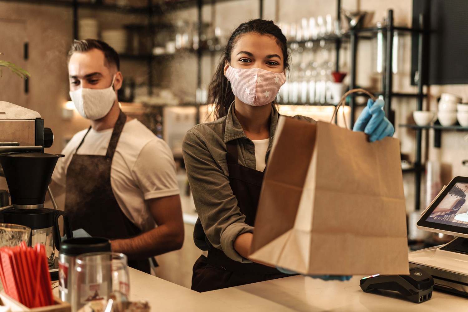 Young people working in coffee shop with surgical masks on.