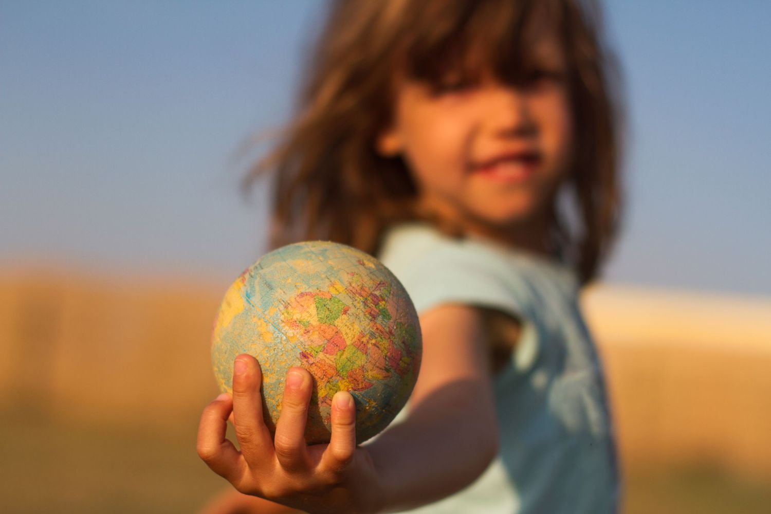 A girl holds a globe in her hand.