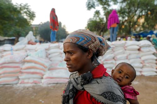 FILE PHOTO: A woman carries an infant as she queues in line for food, at the Tsehaye primary school, which was turned into a temporary shelter for people displaced by conflict, in the town of Shire, Tigray region, Ethiopia, March 15, 2021. Picture taken March 15, 2021. REUTERS/Baz Ratner/File Photo