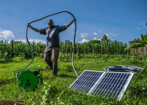 A Kenyan farmer carrying the hose of his solar water pump in Kisumu county, Kenya on June 2018. Handout by Futurepump/Dan Odero