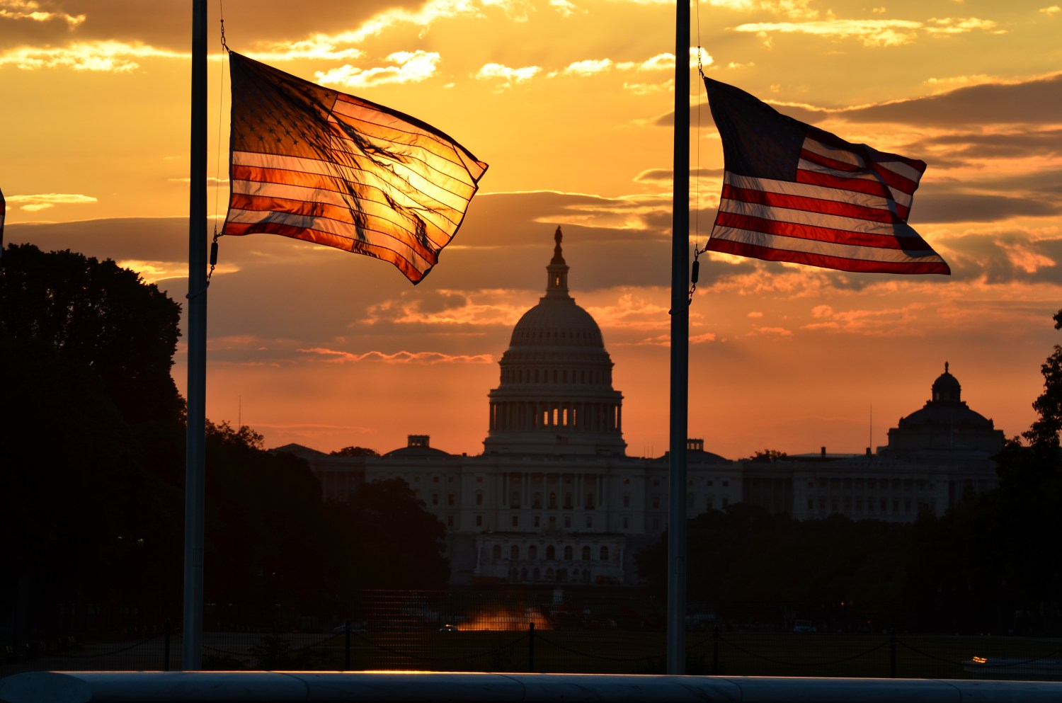 U.S. Capitol building and flags at sunrise
