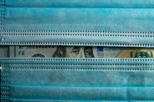 U.S. currency peeking out from behind two surgical masks