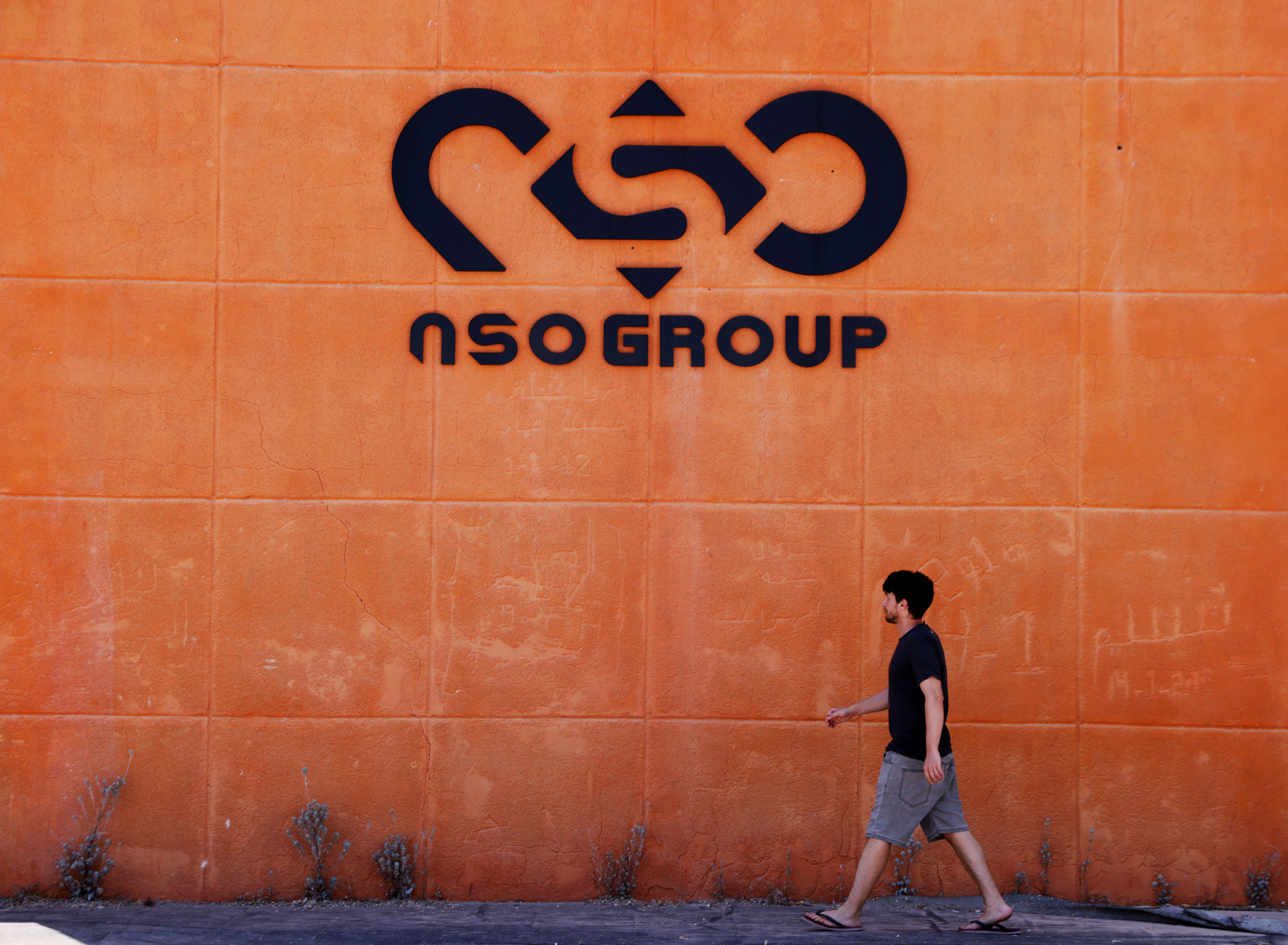 A man walks past the logo of Israeli cyber firm NSO Group at one of its branches in the Arava Desert, southern Israel July 22, 2021. REUTERS/Amir Cohen