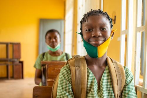 A girl in Nigeria smiles in her classroom.