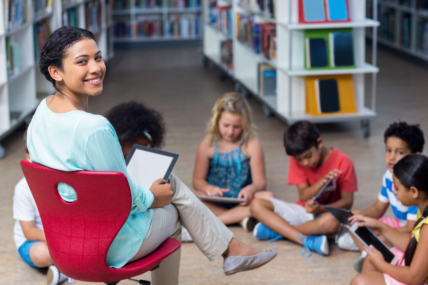 A daycare teacher reads a book to her students.