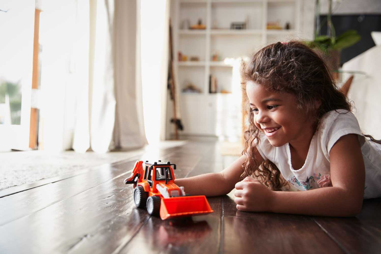 A girl plays with a toy bulldozer.