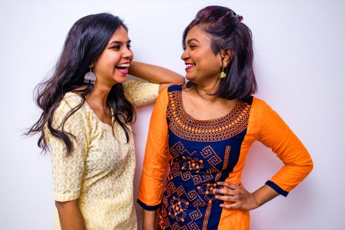 two Indian woman in kurta posing over white wall