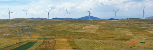 Panoramic view of yellow fields with a line of windmills. Montenegro, Niksic, Krnovo wind park