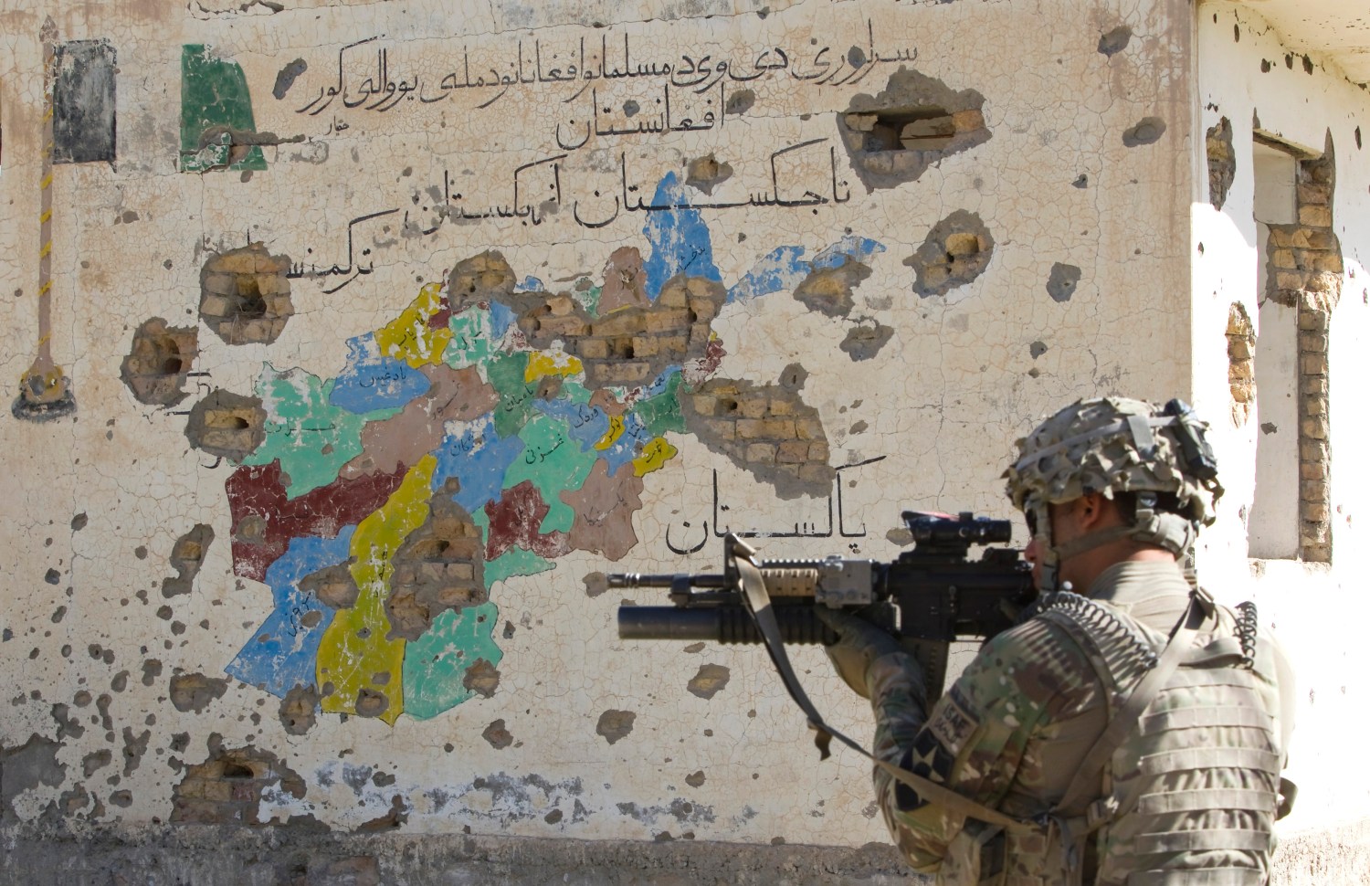 A U.S. Army soldier of 5-20 Infantry Regiment attached to 82nd Airborne Division, aims his rifle in front of a bullet riddled map of Afghanistan painted on a wall of an abandoned Canadian-built school in the Zharay district of Kandahar province, southern Afghanistan June 9, 2012.  REUTERS/Shamil Zhumatov  (AFGHANISTAN - Tags: MILITARY CIVIL UNREST POLITICS)