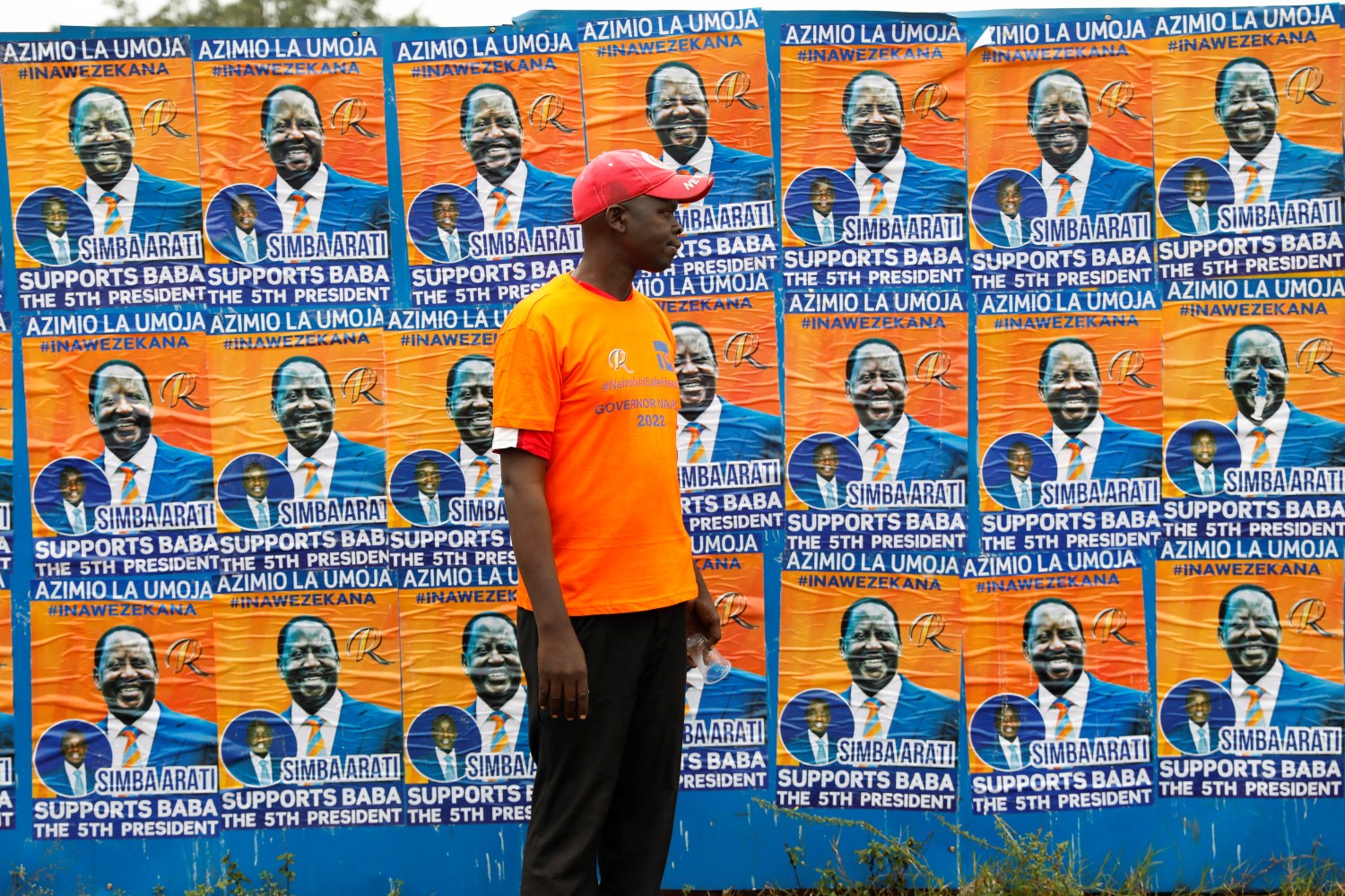 A supporter of Kenya's Opposition leader Raila Odinga walks past his election posters before the Azimio la Umoja (Declaration of Unity) rally to unveil his August 2022 Presidential race candidature at the Moi International Sports centre in Kasarani, Nairobi, Kenya December 10, 2021. REUTERS/Baz Ratner
