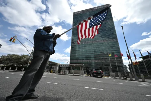 A man stands across the street from the United Nations Headquarters waving an U.S. flag